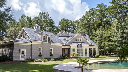 gray timber clad home with large backyard and pool