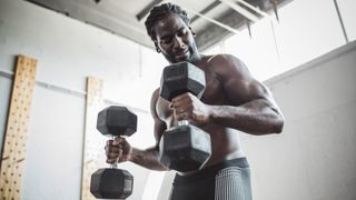 Man performs hammer curl exercise using heavy dumbbells