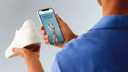 A man using a smartphone to scan a digital ID tag on the back of a white sneaker