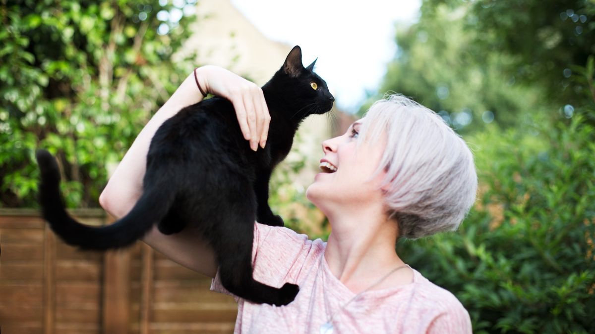 Woman outside with black cat 