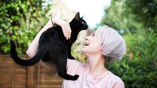 Woman outside with black cat 