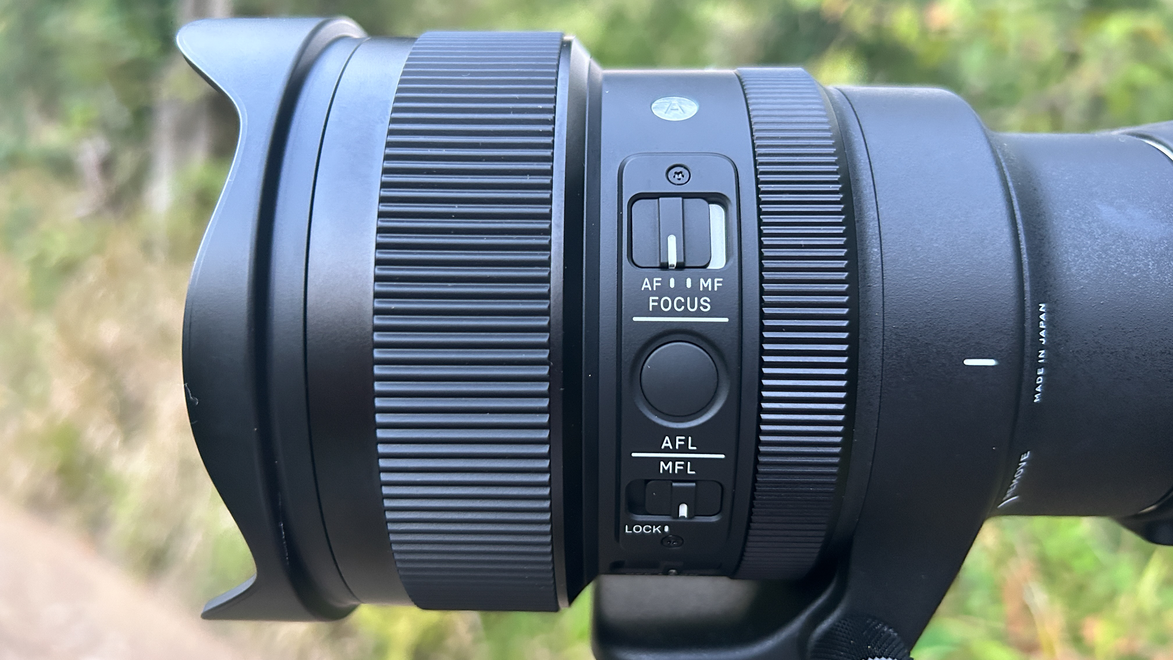 A black camera lens with two ridged adjustment rings is mounted to an out-of-frame tripod.