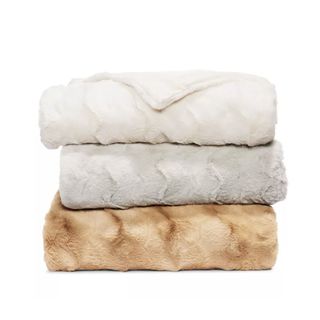 three folded faux fur throw blankets in white, grey, brown