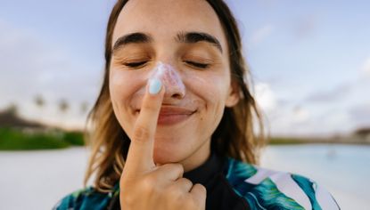 woman applying sunscreen on the beach on her nose