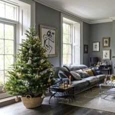 Decorated Christmas tree in woven basket in living room with fireplace