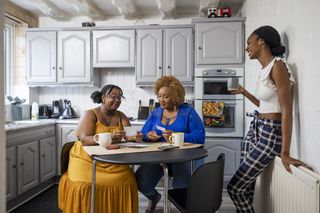 three women socialising around their kitchen table at home
