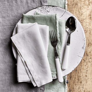 White serving platter with tableware and cloth placed on top
