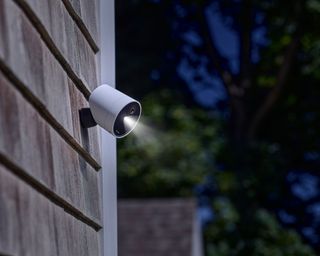 a security camera on the side of a house in night time with a spotlight shining down