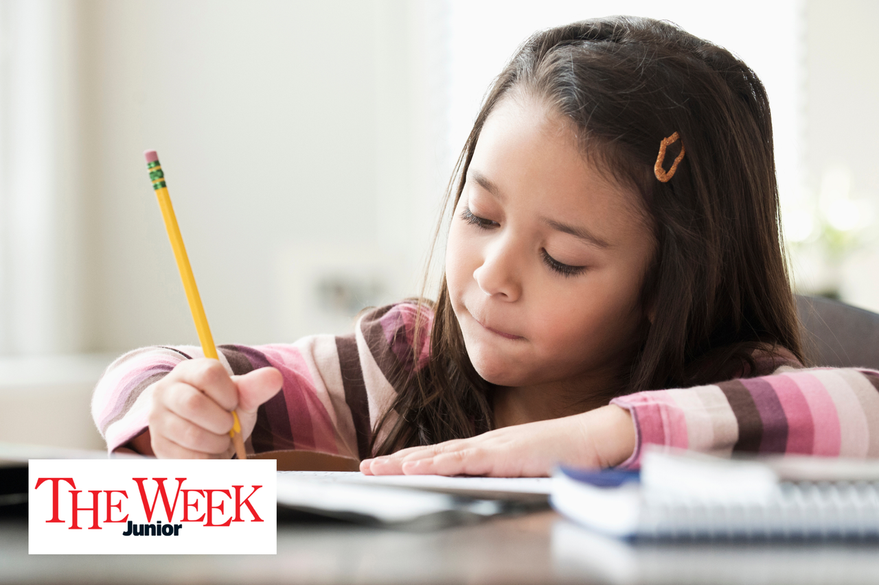 A girl sitting at desk and writing in a journal 