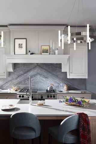 a white shaker style kitchen with bookmounted granite splashbacks and kitchen island