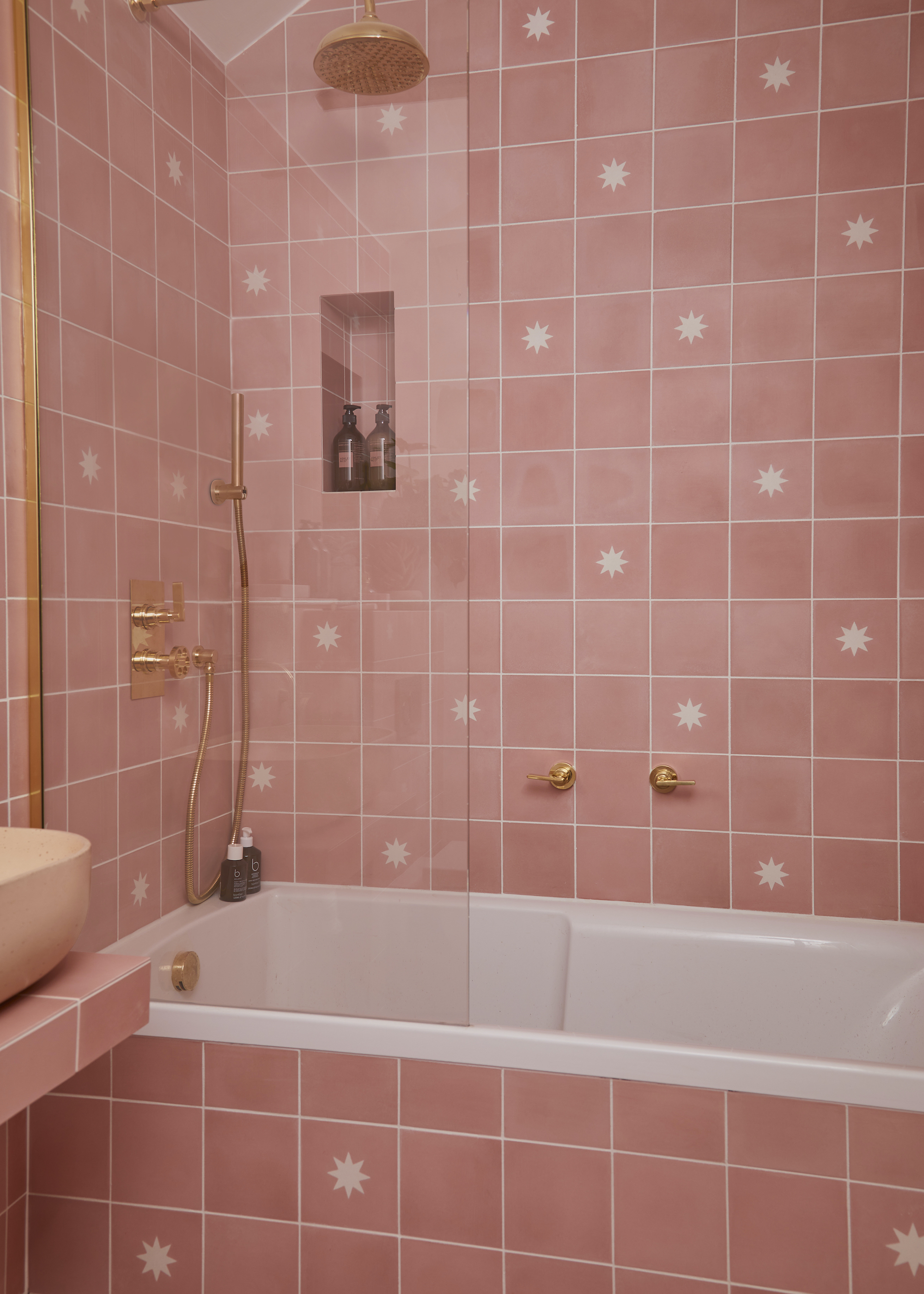 A bathroom with pink tiles all around as well a bathtub and a shower