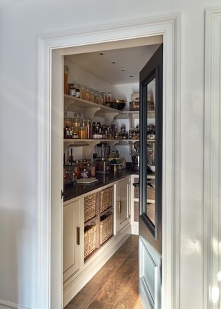 A kitchen pantry with dark countertops and black door.