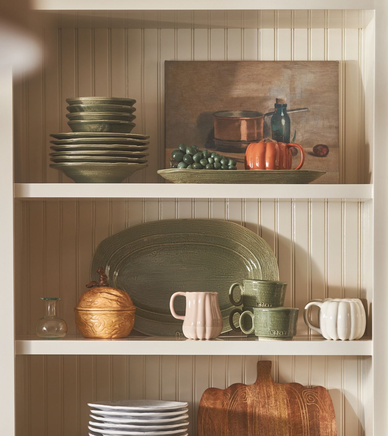 A kitchen with pumpkin-shaped mugs, a water jug and plates
