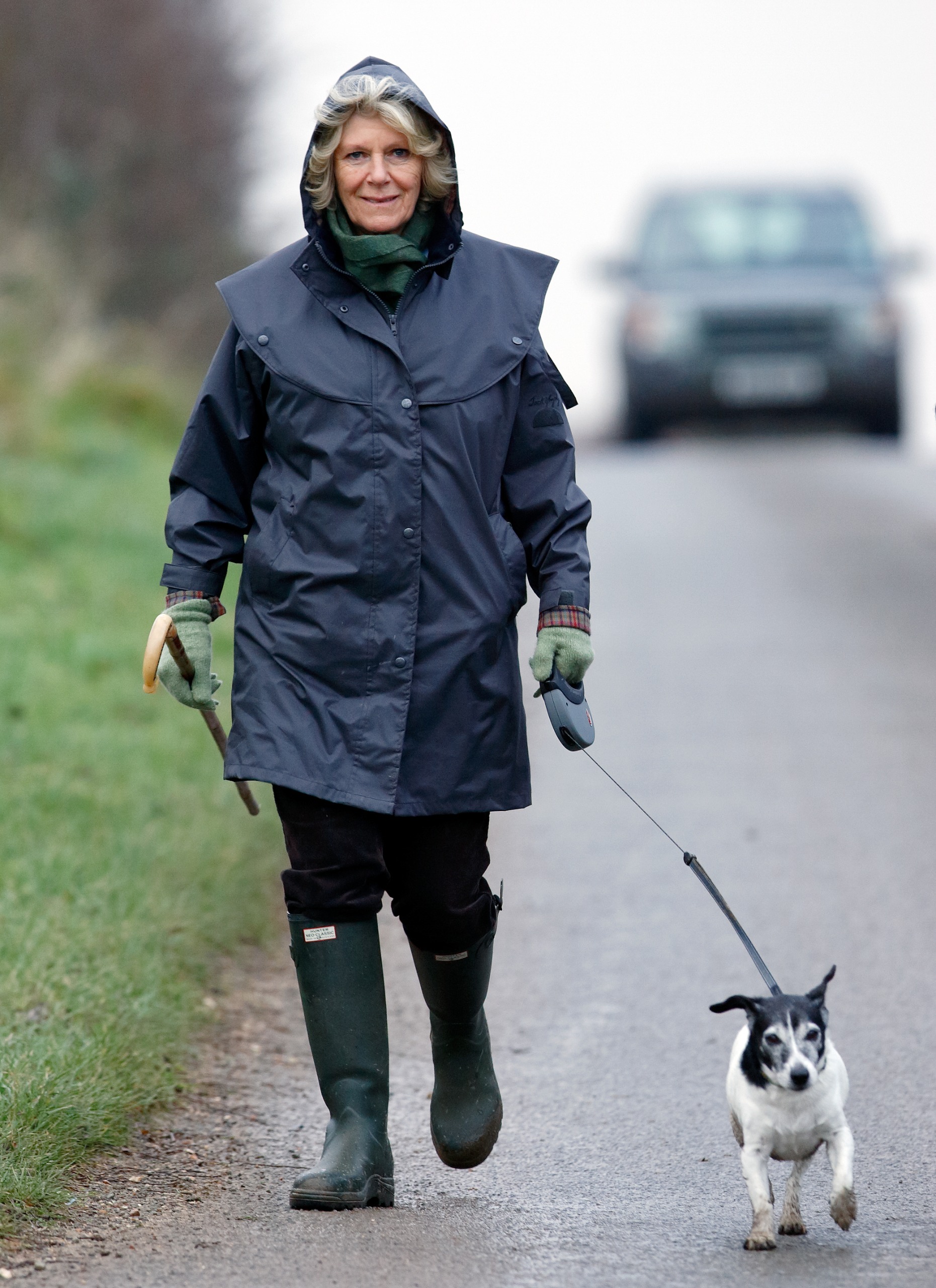 Queen Camilla walking her dog in a rain coat and Hunter boots