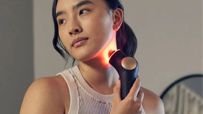 Woman using the Therabody TheraFace PRO on her neck
