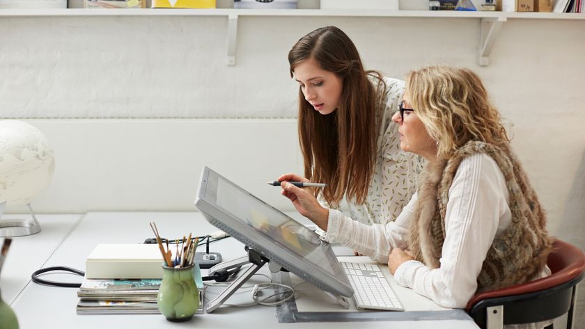 woman showing a younger woman something on a drawing tablet