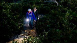 Woman holding torch and walking with man through trail