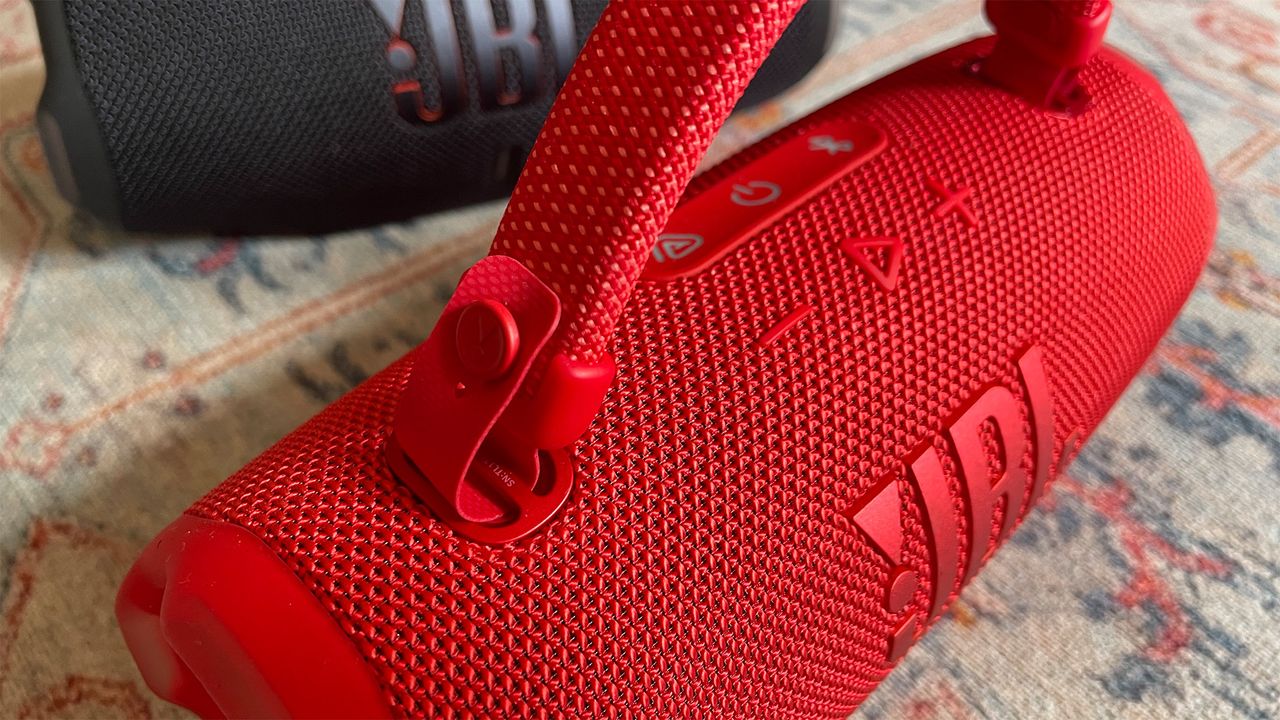 A close-up of the integrated handle on a red JBL Charge 6 wireless speaker.