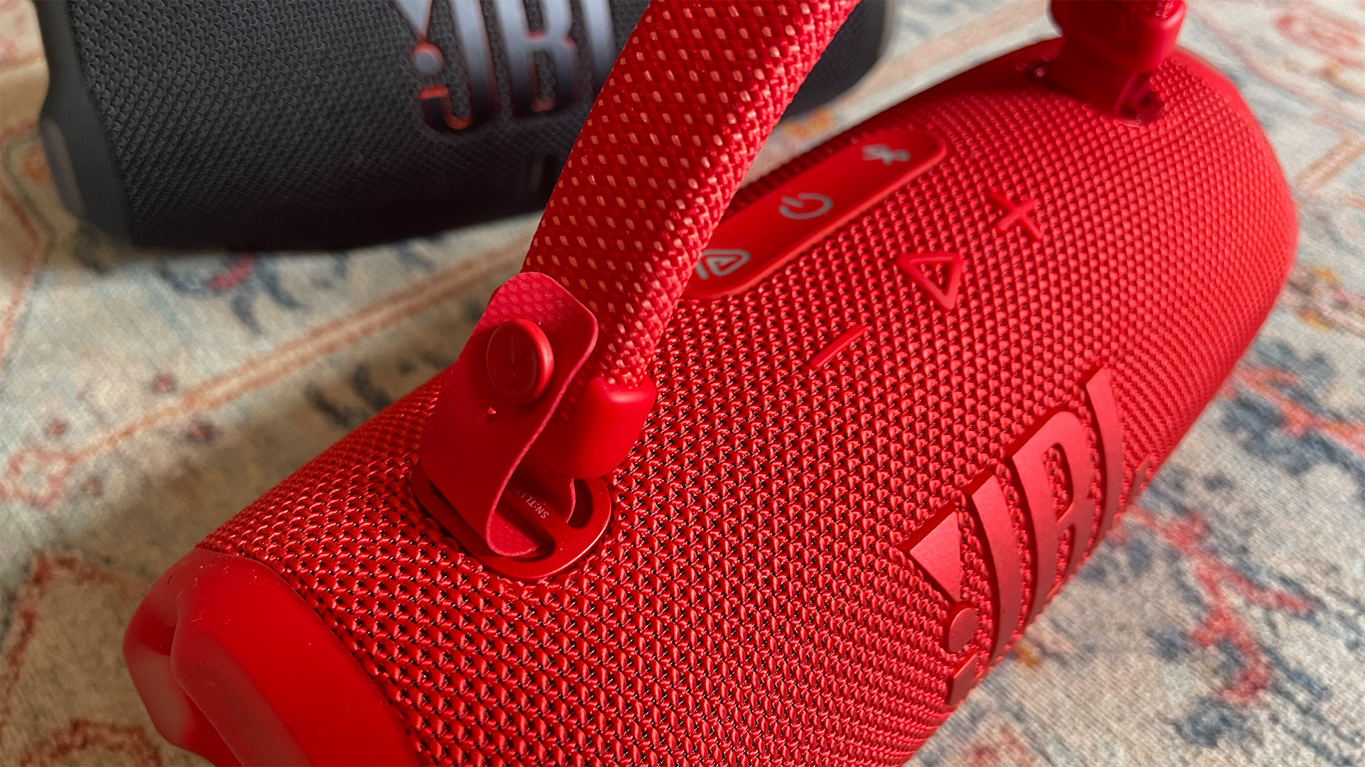 A close-up of the integrated handle on a red JBL Charge 6 wireless speaker.