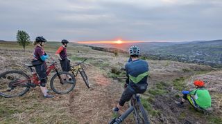 Mountain bikers looking out over a sunset