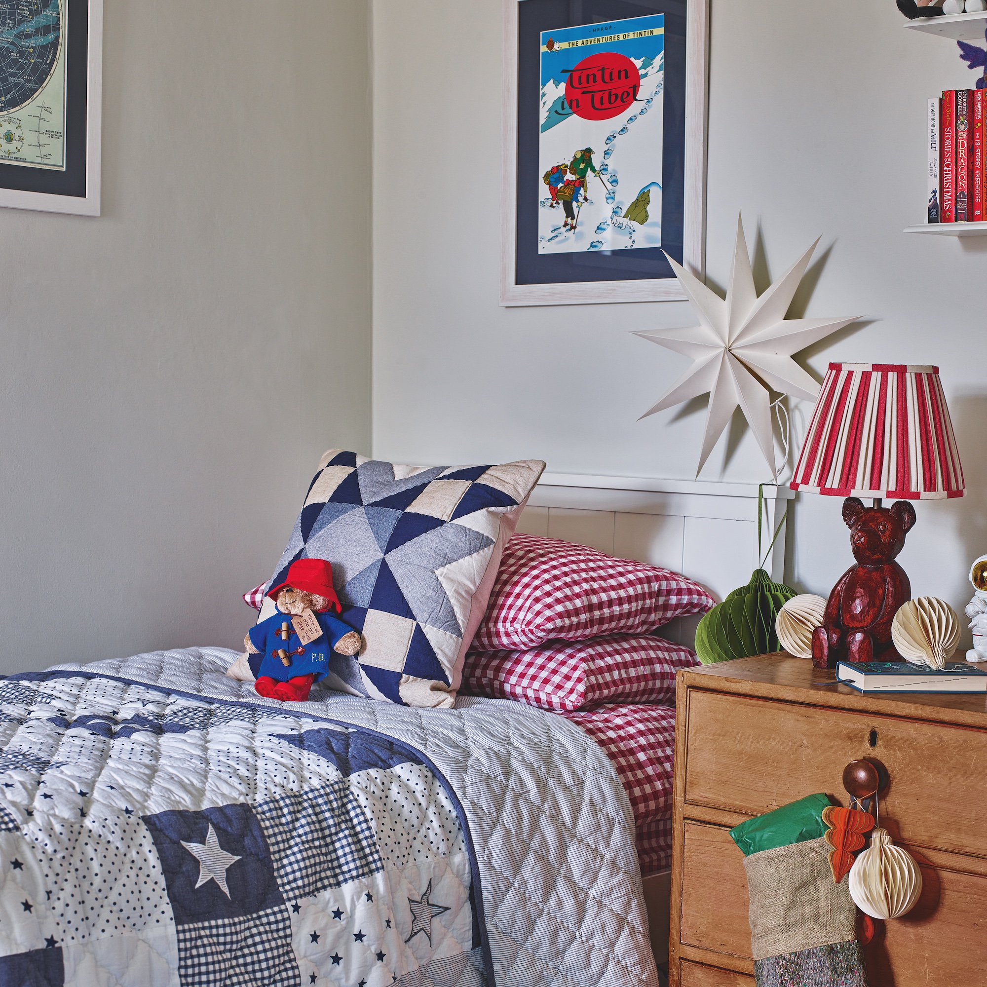 childs bedroom with white walls and blue patchwork quilt and cushion on bed