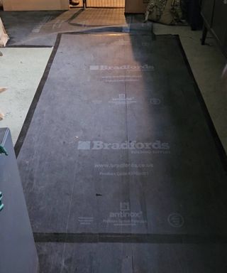 black floor protection boards on top of green carpet during renovation