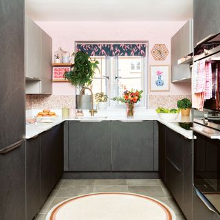 Pink painted kitchen with grey cabinets, terrazzo hexagon tile splashback, gold tap