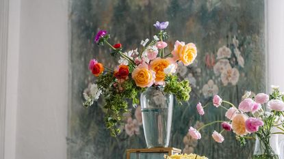Pink red yellow and orange spring flowers in vase on green floral background