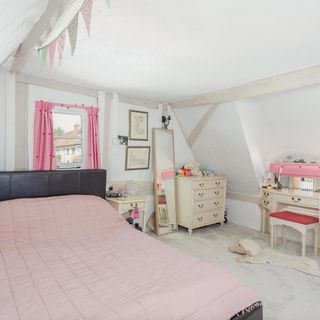 thatched house bedroom with pink curtains and mirror