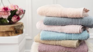 Pink, grey, blue, and beige towels stacked on top of one another: how to keep towels soft