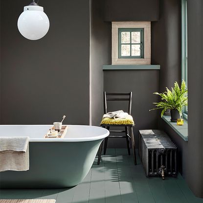 bathroom with grey shade wall and grey bathtub and wooden floor and chair and towel