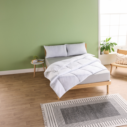 Aldi cooling bedding on a double bed in a bedroom with green walls.