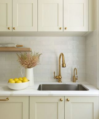 neutral kitchen with with subway tiles and a brass faucet