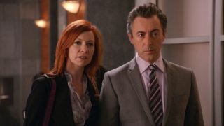 From left to right: Carrie Preston as Elsbeth and Alan Cumming as Eli tanding and looking forward.