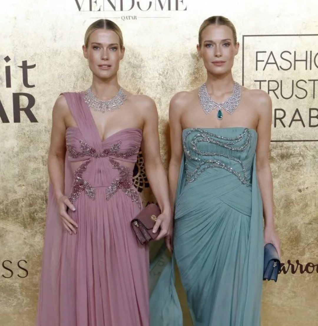 Amelia and Eliza Spencer posing in pastel gowns in front of a Fashion Trust Arabia backdrop