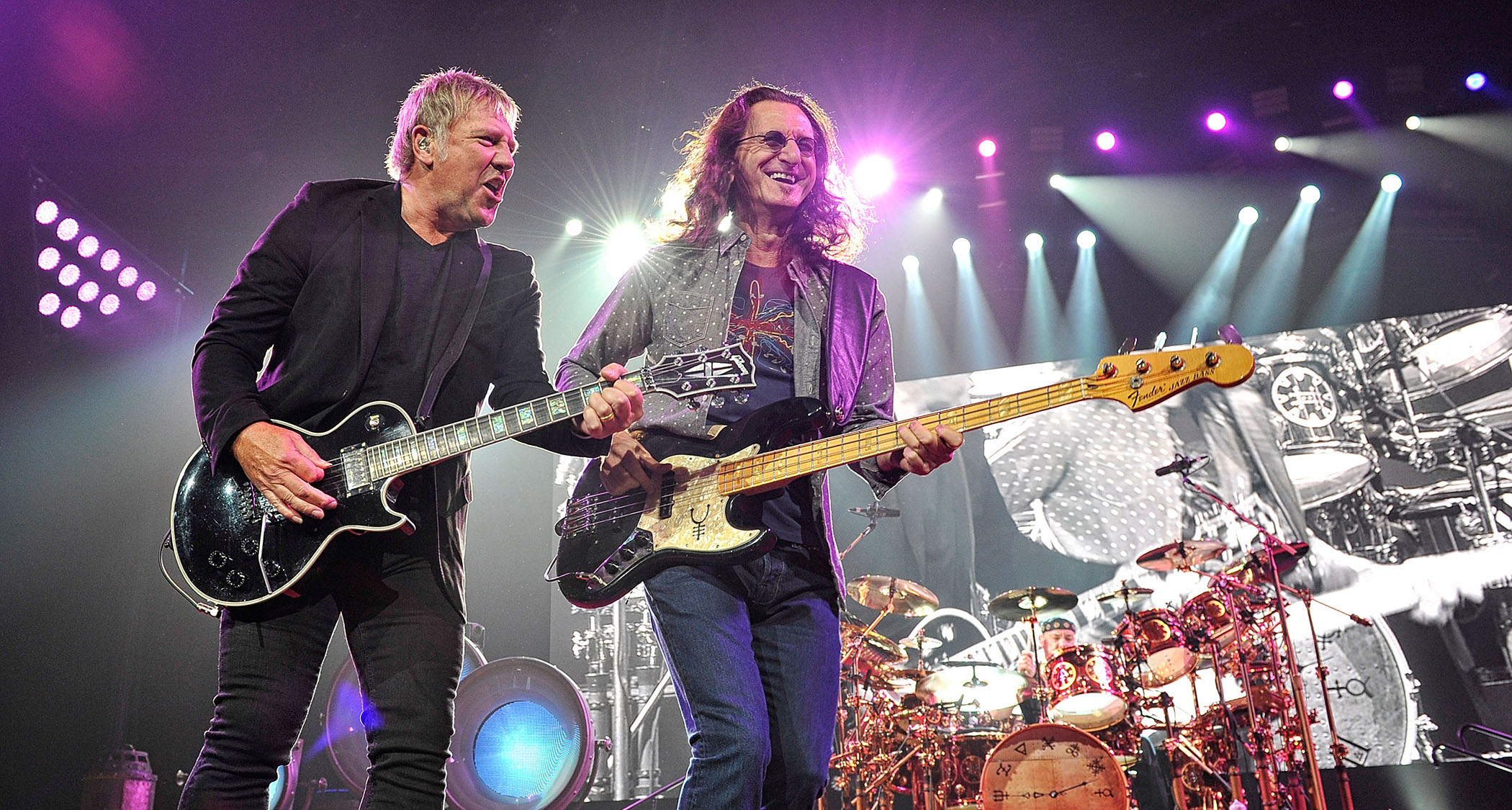 Alex Lifeson [left], Geddy Lee and Neil Peart [background] perform with Rush in 2013.