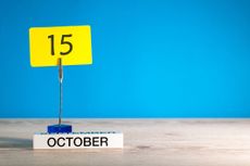 desk photo holder holding up the number 15 on a bright yellow notecard, with an October block underneath against a bright blue background