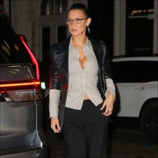 Bella Hadid in an unbuttoned striped button-down shirt and glasses