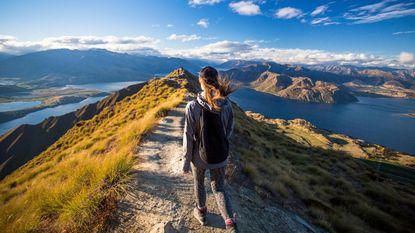 A woman walks on a mountain path.