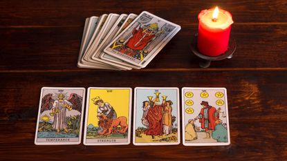 On the table are fortune-telling tarot cards and lighted candle.Magic sessions with clairvoyance cards.Reading maps by candlelight.