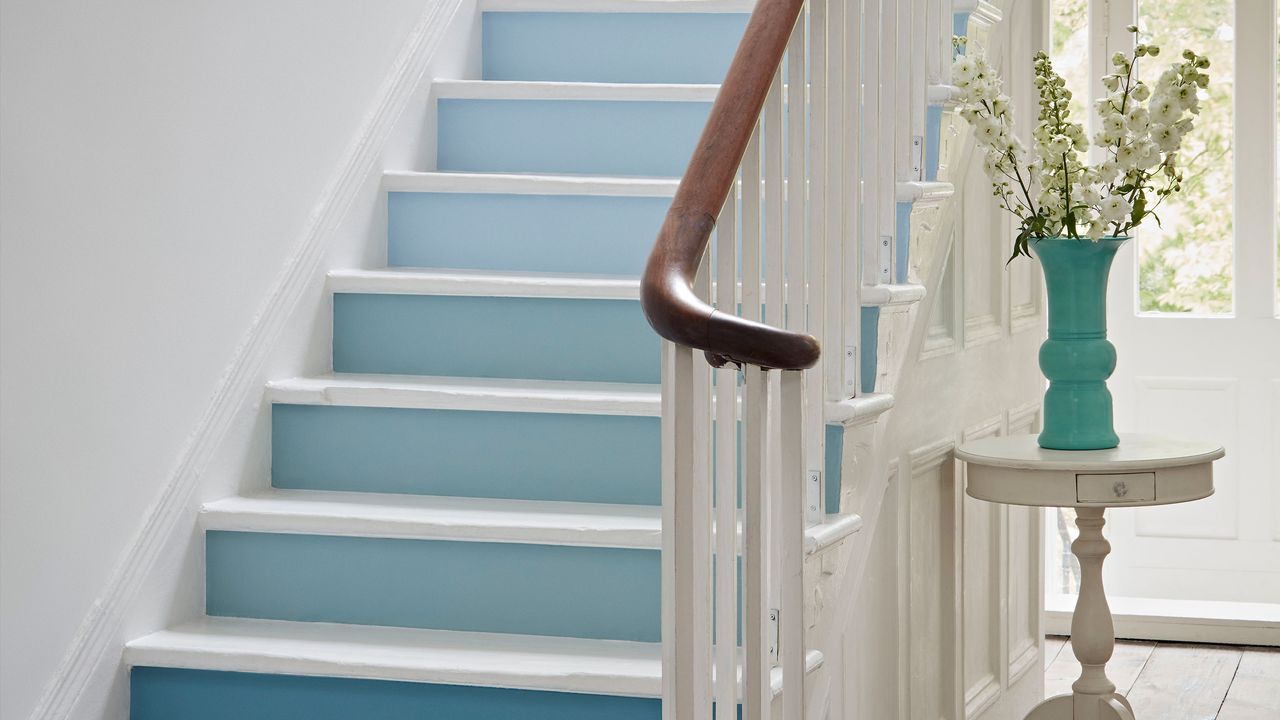 White hallway with white stair risers painted in shades of blue to create an ombre effect