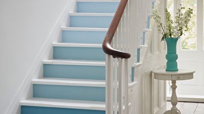 White hallway with stair risers painted in shades of blue to create an ombre effect