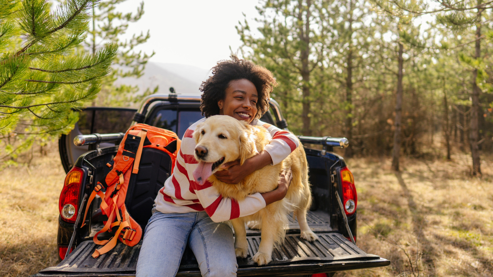 smiling woman hugging her dog in the bed of a truck