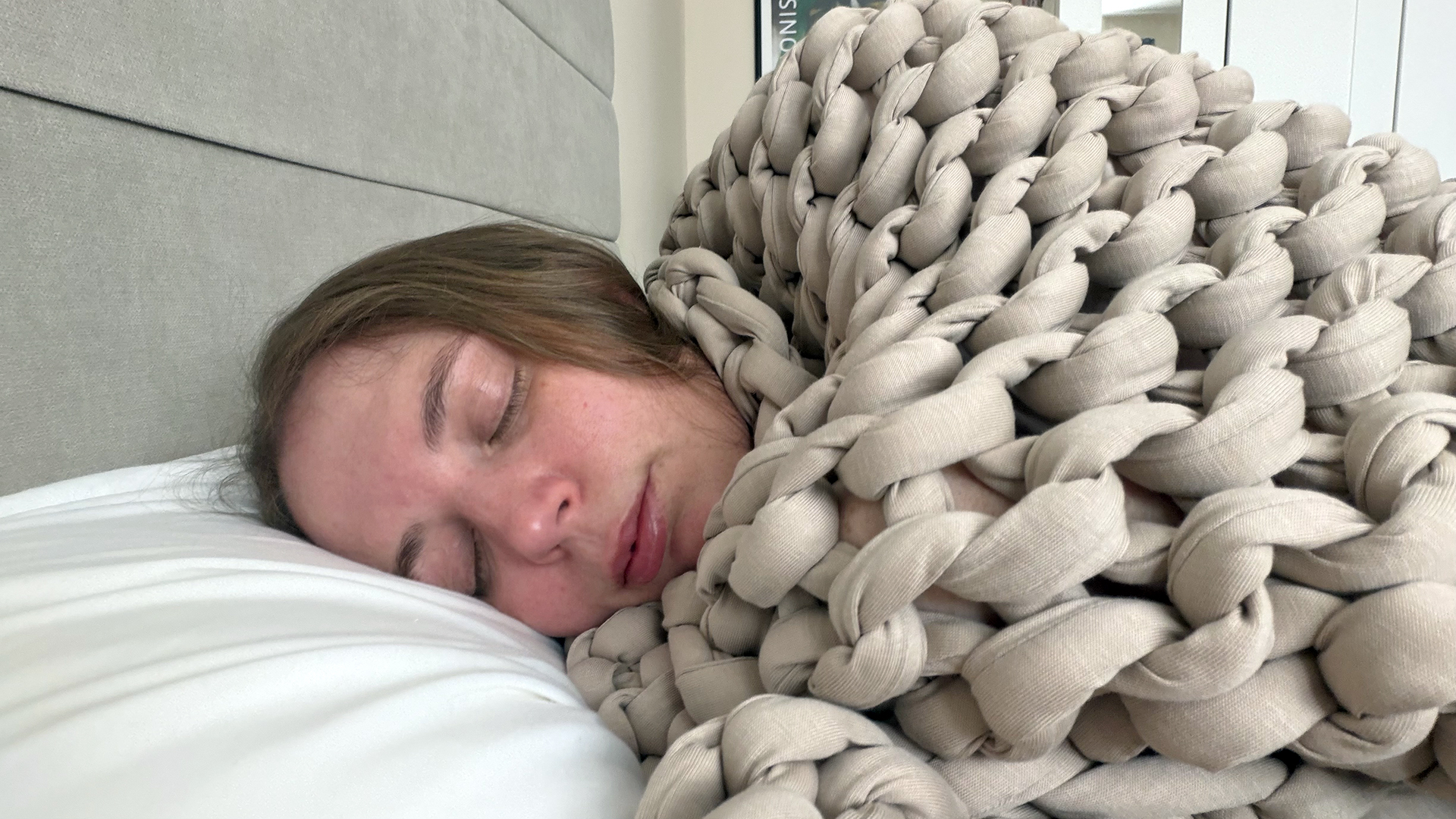A close up of tester Ruth Jones wrapped up in the Bearaby Tree Napper weighted blanket