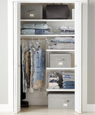 A closet with items of clothing hung using hangers on clothing rail and vacuum clothing bags