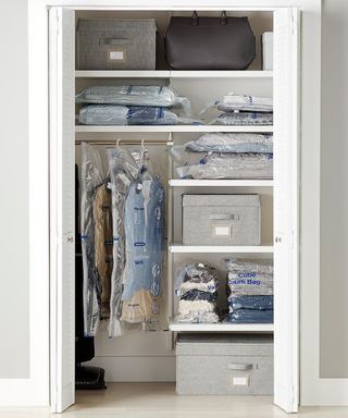 A closet with items of clothing hung using hangers on clothing rail and stacked vacuum clothing bags