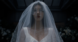Camila Morrone in Something Very Bad Is Going to Happen dressed in a white bridal gown and veil