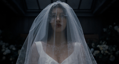 Camila Morrone in Something Very Bad Is Going to Happen dressed in a white bridal gown and veil