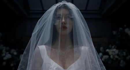 Camila Morrone in Something Very Bad Is Going to Happen dressed in a white bridal gown and veil