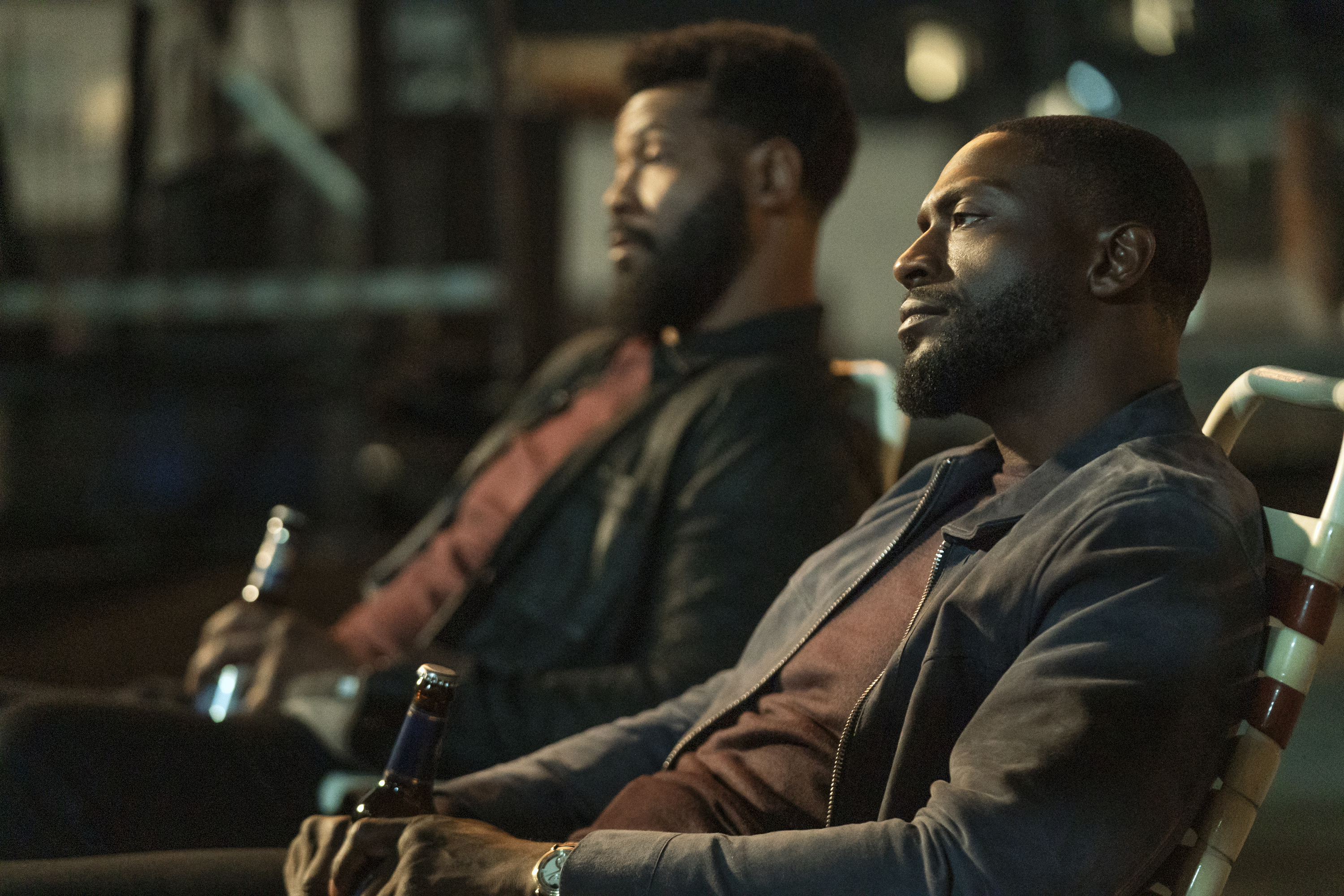 John Sampson (Isaiah Mustafa) and Alex Cross (Aldis Hodge) sit in lawn chairs drinking beers at night in a still from cross season 2